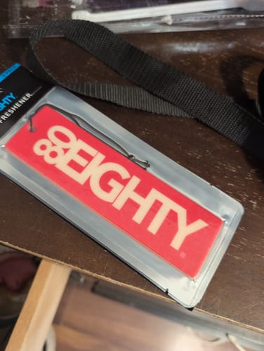 Customer's red 80Eighty Smoke Ice Air Freshener in its original clear packaging, resting on a table.