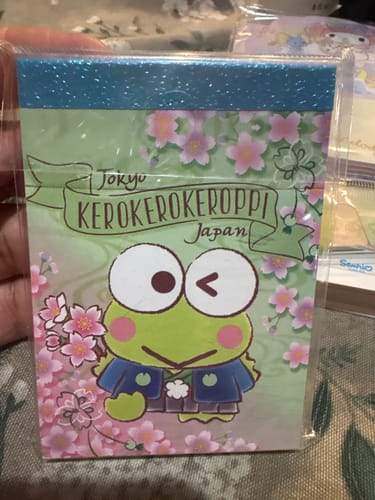 Customer holding a Sanrio Keroppi memo pad with a cute cherry blossom design, still in its plastic packaging.