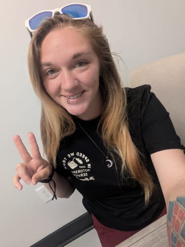 Customer wearing the black Motorsport Service shirt, smiling and making a peace sign.