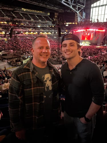 Customer wearing the Whiskey Golden Retriever Grunge T-Shirt under a plaid flannel shirt at a concert.