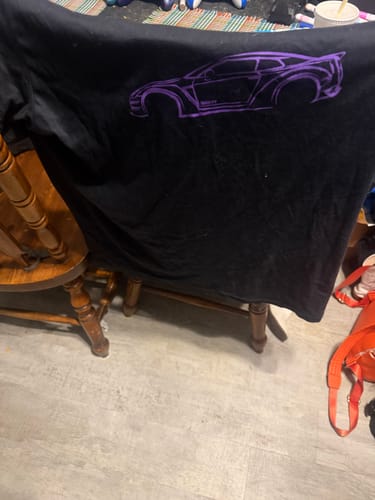 A customer's black 80Eighty® DCG88 Shirt with a purple car graphic, draped over a chair.