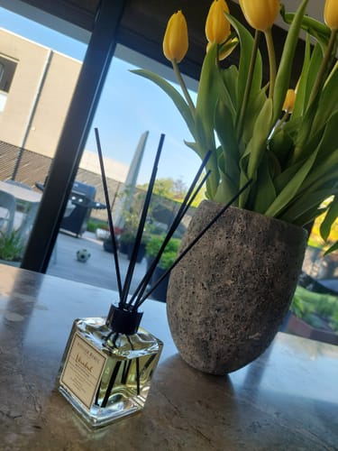 Recensent toont de Istanbul Bosphorus Parfum op een aanrechtblad naast een vaas met gele tulpen.