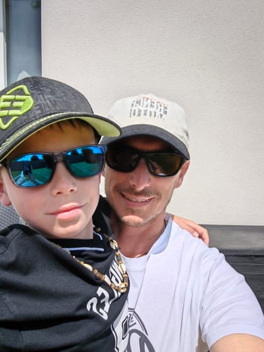 Client posant avec un enfant, portant des casquettes et des t-shirts de la COLLECTION ORANGE DISTRICT.