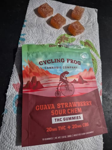 Reviewer shows the Guava Strawberry Rosin Gummies packaging with four square, sugar-dusted gummies arranged beside it.