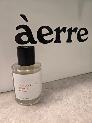 Customer's London City Lights perfume bottle with a black cap, displayed in front of a branded bag.