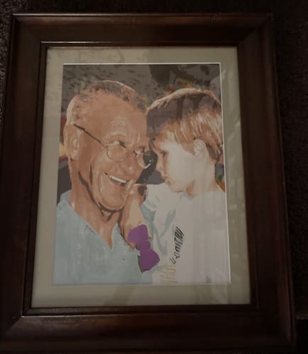 Customer's finished Custom Paint By Numbers portrait of an older person and a child, displayed in a dark wood frame.