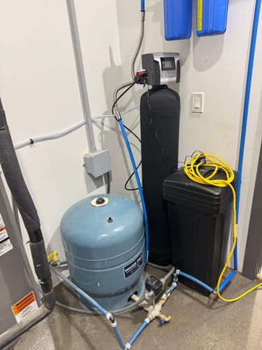 Customer's installed SoftPro® Elite HE Water Softener in a utility room next to a pressure tank.