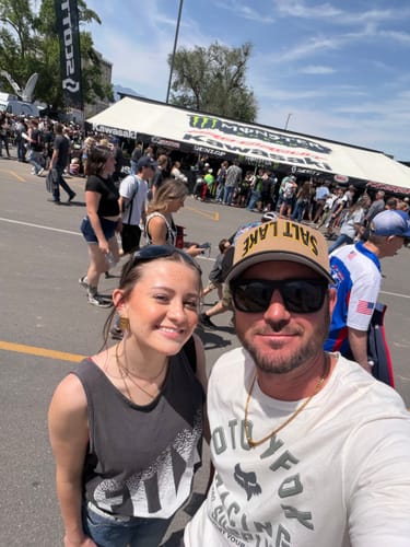Customer wearing the Legacy Necklace over a white t-shirt at a busy outdoor event.