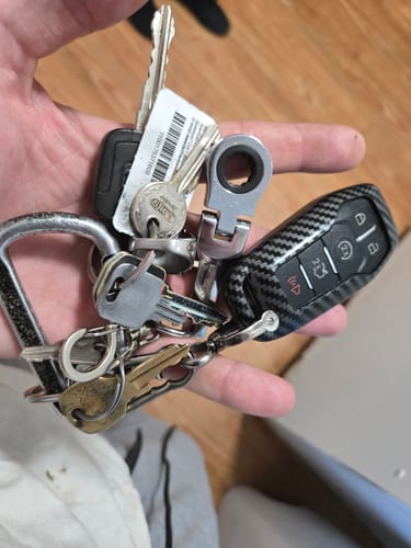 Reviewer holding a full keyring in their hand, showing the attached silver 10mm Wrench Keychain.