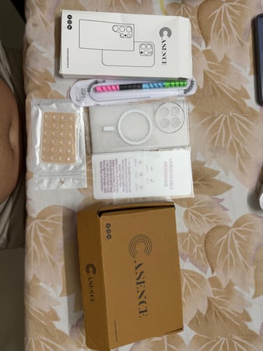 Customer's Anti Yellow Magsafe Clear Case laid out with its packaging and several freebies on a patterned surface.