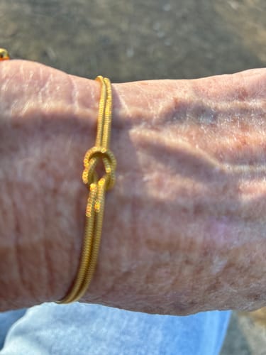 Close-up of a customer wearing the gold-colored knot bracelet on their wrist.
