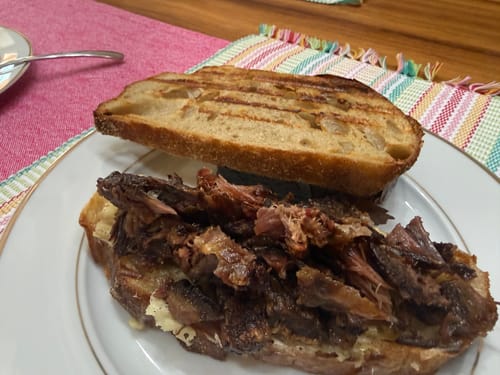 Un cliente muestra la Carne Seca Original preparada en un abundante sándwich sobre pan a la parrilla.