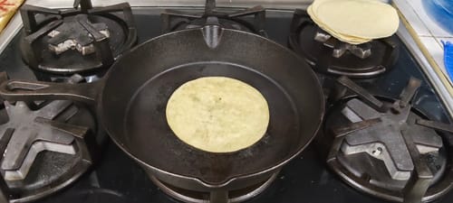 Cliente calentando una Tortilla Taquera de Harina Becarel en un comal sobre la estufa.