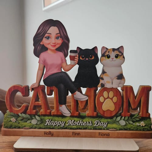 Customer's personalized 'CAT MOM' wooden plaque with an animated woman and two cats sitting on a base engraved with names.