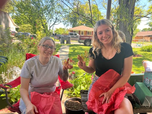 Two reviewers smiling outdoors while holding their personalized sunflower suncatchers.