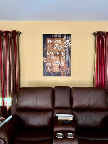 Customer's beautiful Tailored Boost canvas with a faith message hanging on a wall above a brown leather couch.