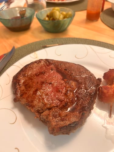 Customer's juicy, cooked AAA Ribeye Steak served on a white plate.