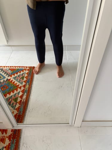 Cliente portant le legging de sport bleu foncé, photographié de face dans un miroir.