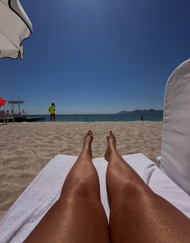 Reviewer's glowing, tanned legs on a beach towel, showing the results of the Complete Glow Bundle.