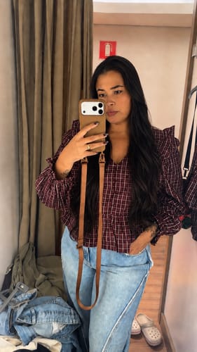 Cliente mostrando a Case Mocha Mousse marrom em seu celular, usada com a alça.