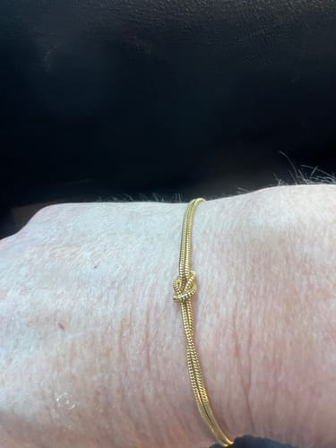 Customer wearing the dainty gold Forever Knot Bracelet on their wrist.