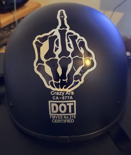 Reviewer's flat black SOA Beanie helmet with a large custom skeleton hand sticker on the back above the DOT certification.