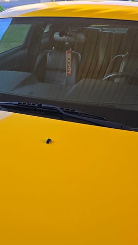 Customer's red 80Eighty Air Freshener hanging from the rearview mirror inside a yellow car.