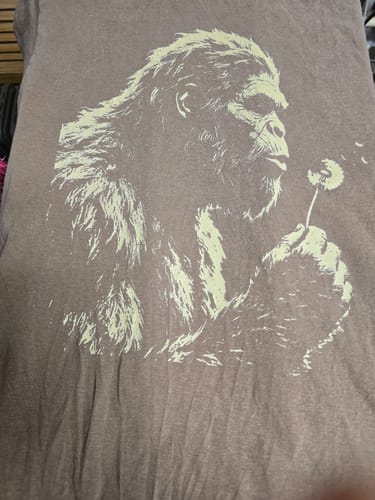 Customer's close-up of the brown Blowing Wishes T-Shirt, showing the graphic of Bigfoot blowing a dandelion.