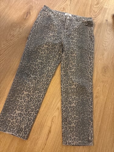 Kundenfoto der Jeans Mom Fit FEARLESS LEO mit Leopardenmuster, die auf einem Holzboden liegt.