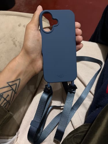 Cliente segurando uma capa de celular com a Alça Aurora Azul da Cor do Mar já conectada.