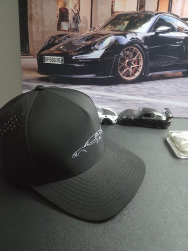 Reviewer's black DCG89 Hat on a desk showing the perforated side and car logo.