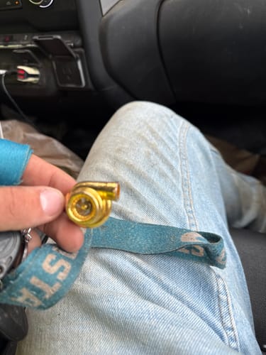 Customer holding the small, gold-colored TURBO KEYCHAIN in their hand while sitting in a car.