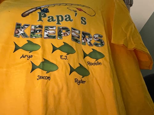 Customer's personalized yellow 'Papa's Keepers' fishing shirt showing five fish with names.
