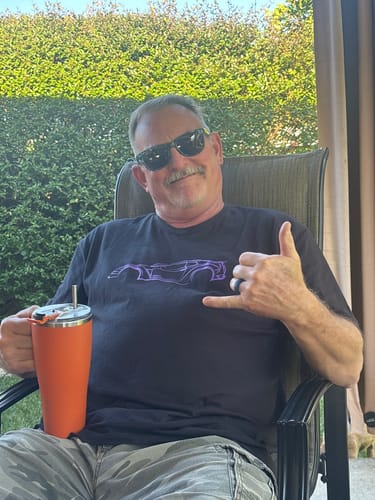 Customer wearing the black 80Eighty® DCG88 Shirt while relaxing in a chair outdoors, making a shaka sign.