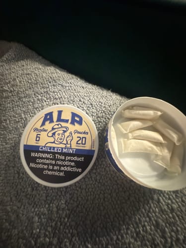 Customer's open tin of ALP Chilled Mint Nicotine Pouches with several white pouches visible inside.