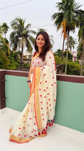 Reviewer wearing the off-white Love Embroidery Saree, showing the red heart pattern and gold border.
