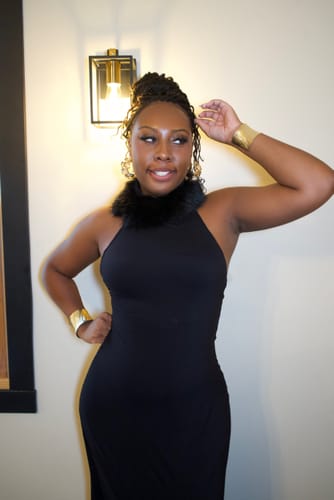 Reviewer wears the black Naked Faux Fur Maxi Dress with its faux fur halter collar.