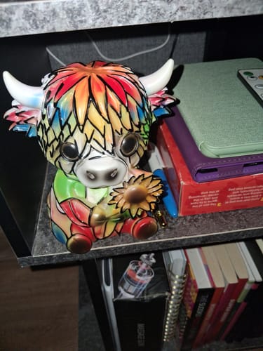 Reviewer's colorful, mosaic-style Highland Cow LED Night Light shown unlit on a shelf.