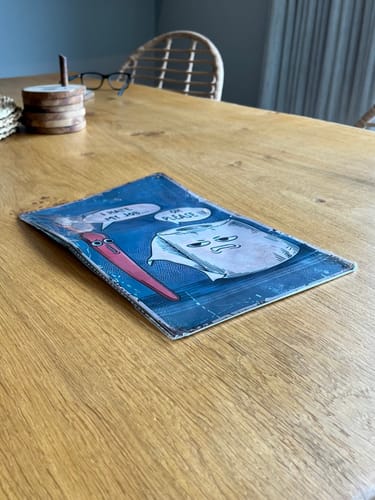 Customer's 'I Hate My Job Oh Please' funny wall art, shown damaged and bent on a wooden table.