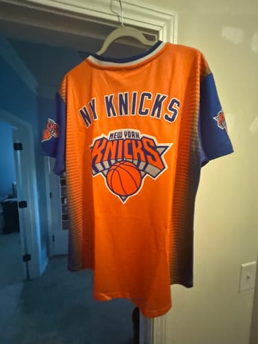 Reviewer's orange and blue NY Knicks baseball jersey on a hanger, showing the back with the team name and logo.