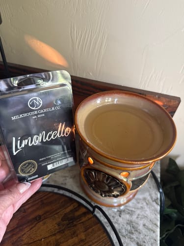 Customer holds the Limoncello Soy Wax Melt packaging next to a lit wax warmer with melted wax.