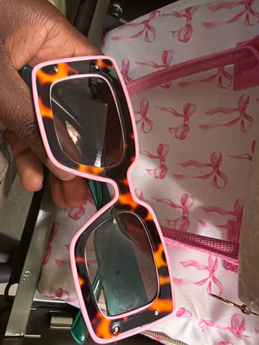 Customer holds up their Deco Sunglasses, showing the stylish tortoiseshell and pink color-block frames.
