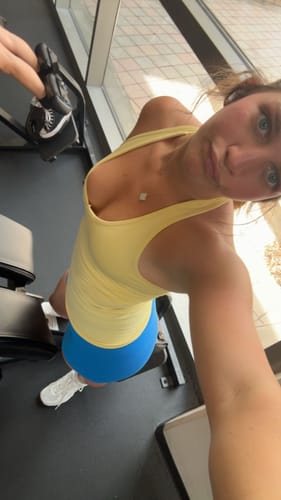 Reviewer at the gym wearing a yellow, form-fitting Curve Seamless Tank, shown from a high angle.