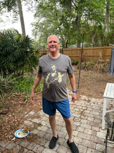 Customer standing on a patio and smiling while wearing the grey Lincoln Guitar T-Shirt.