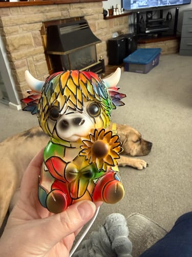 Reviewer holding the Highland Cow LED Night Light, showing its colorful, painted finish in a living room.