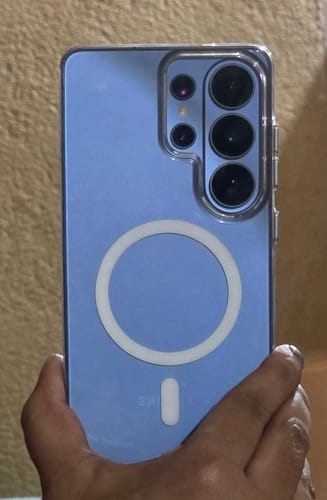 Customer holding a blue Samsung phone in the clear Anti Yellow Magsafe Case, showing the white magnetic ring.