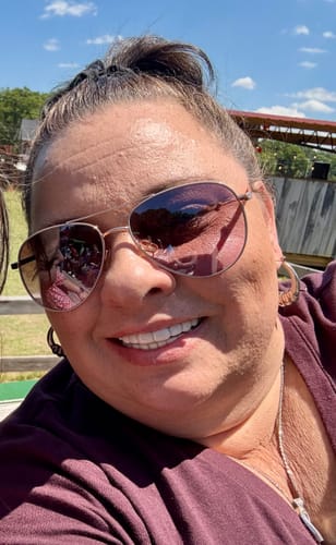 A reviewer smiling outdoors, showing off her bright Pop On Veneers.