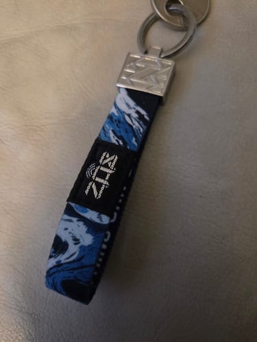 Close-up of a reviewer's Nothing Can Stop You Tiger Bracelet on a keychain, showing the blue abstract pattern.