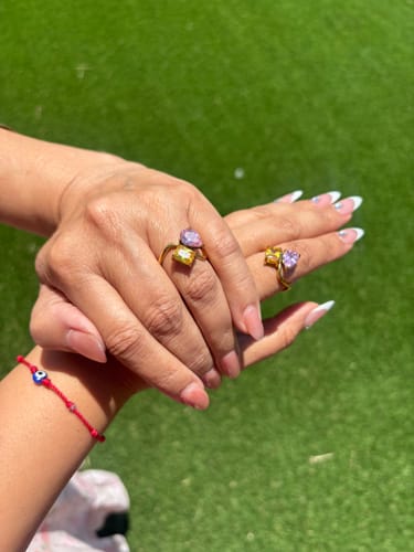 Reviewer shows two matching Navae Birthstone Rings on hands held together, sparkling in the sun.