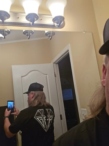 Customer taking a mirror selfie to show the white diamond graphic on the back of their black Broken Tee.